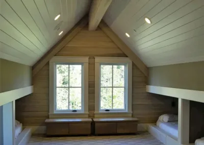 An attic room with two bunk beds and a window.