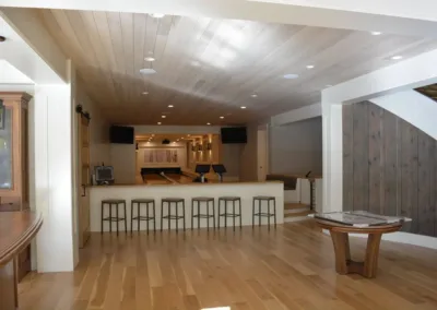 A living room with wood floors and a bar.