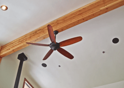 A ceiling fan in a room with wood beams.